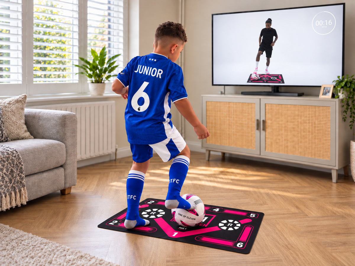 Young footballer practising on a One of Eleven training mat at home while following the training programme on TV